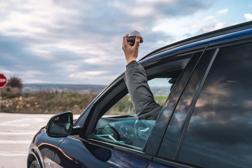 una persona colocando la baliza v16 en su coche