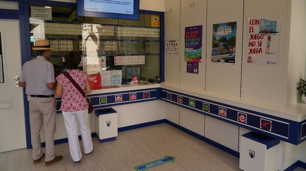 Dos personas comprando en una administración aleatoria de lotería