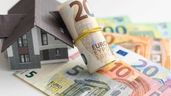 La figura de una casa junto a billetes de euro