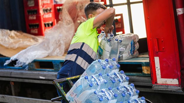 Un repartidor cargado de botellas de agua