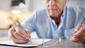 Un anciano firmando un documento 