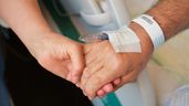 Una persona sujetando la mano a un hombre hospitalizado