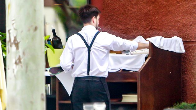 Un camarero de espaldas atendiendo la terraza de un bar