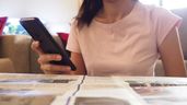 Una mujer con el móvil leyendo el periódico