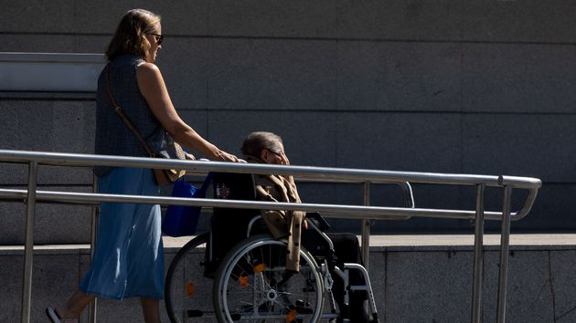 Una persona ayudando a una mujer mayor en silla de ruedas