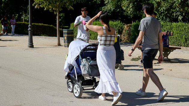 Varias personas pasean con un carrito de bebé