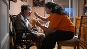 Maricarmen junto a una cuidadora que le da de comer