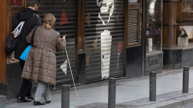 Una persona con discapacidad visual camina acompañada por la calle
