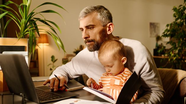Un padre trabajando en el ordenador junto a su hijo