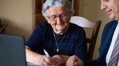 Una anciana firmando un documento