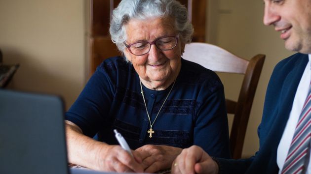 Una anciana firmando un documento