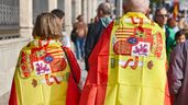 Personas envueltas en bandera de España caminando por la calle