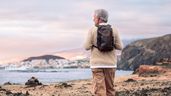 Hombre mayor con mochila en la playa