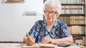 Una anciana firmando un documento 