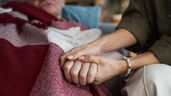 Una mujer agarrando la mano de un familiar enfermo