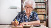Una anciana firmando un documento 