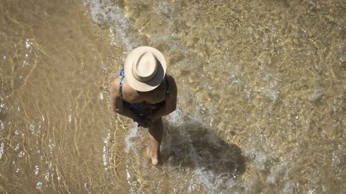 Una mujer mayor paseando por la playa.