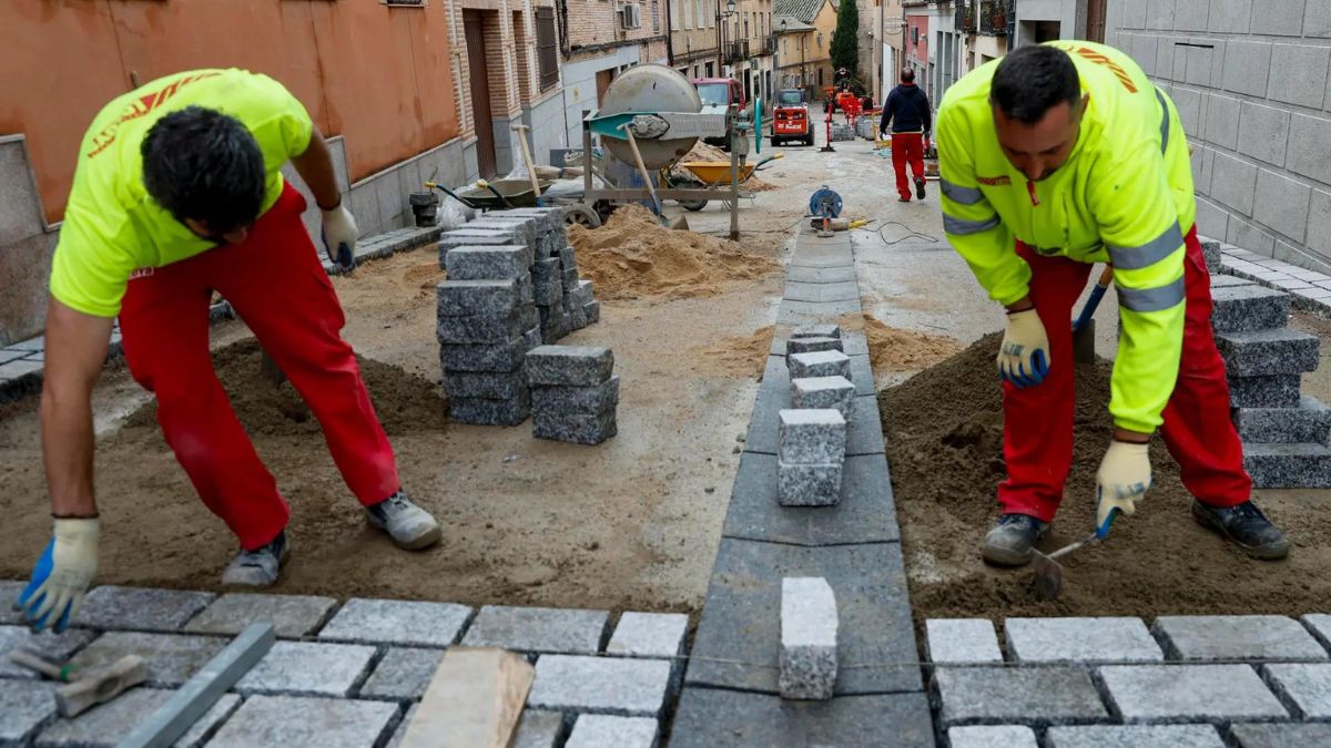 Dos albañiles trabajando en el adoquinado de una calle.