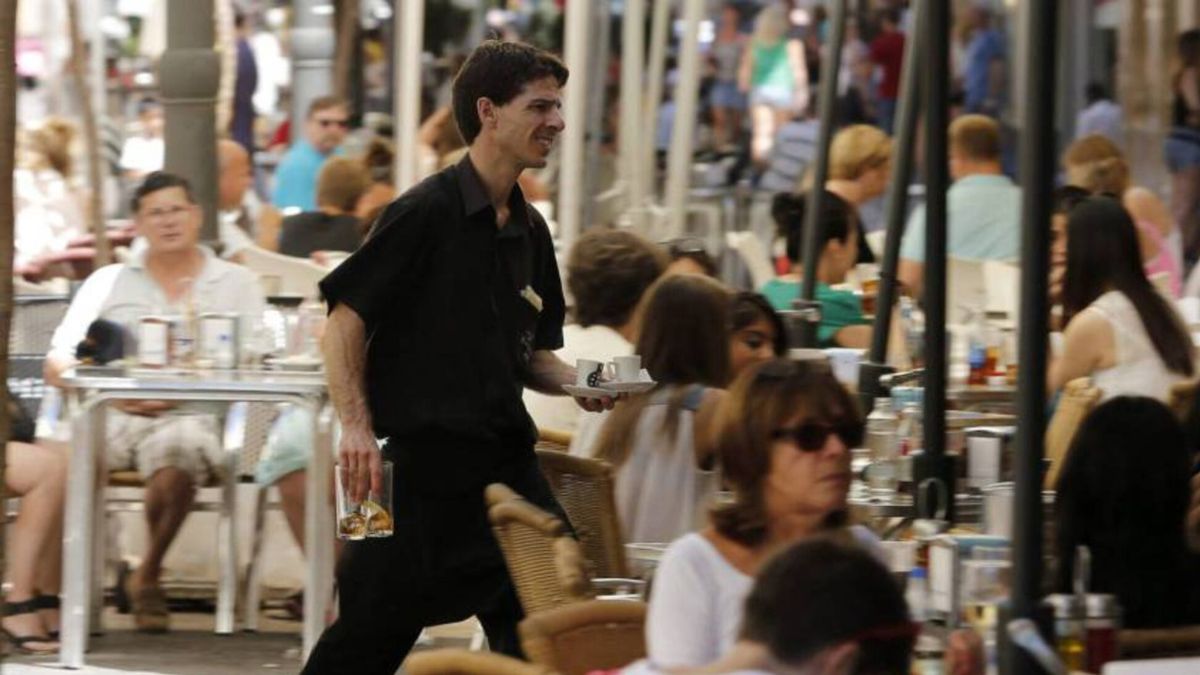 Un camarero recoge vasos en una terraza.