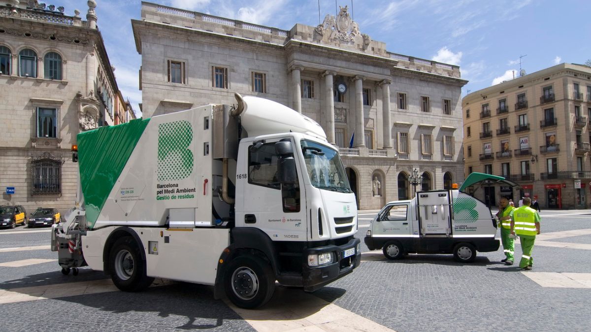 Personal de limpieza junto a un vehículo de limpieza viaria en Barcelona.