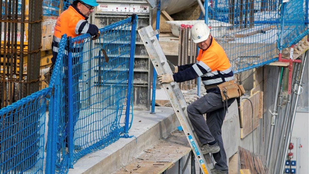 Un albañil sube por una escalera en una obra.