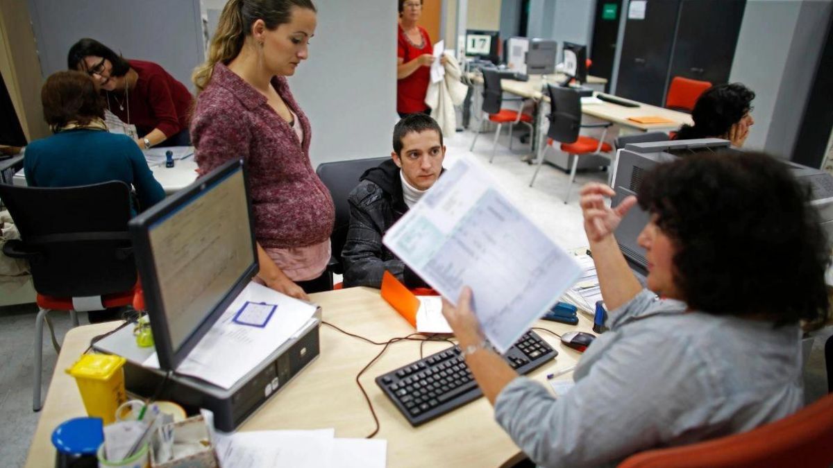 Una auxiliar administrativa atiende a dos personas.