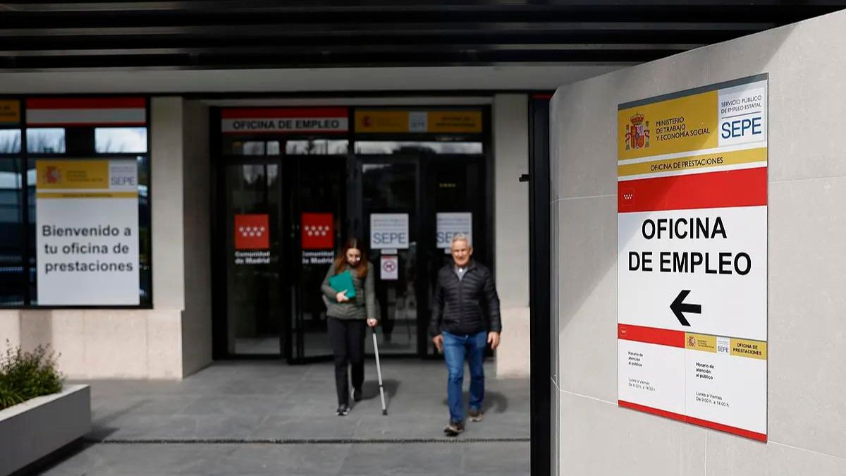 Dos personas salen de una oficina de empleo y prestaciones.