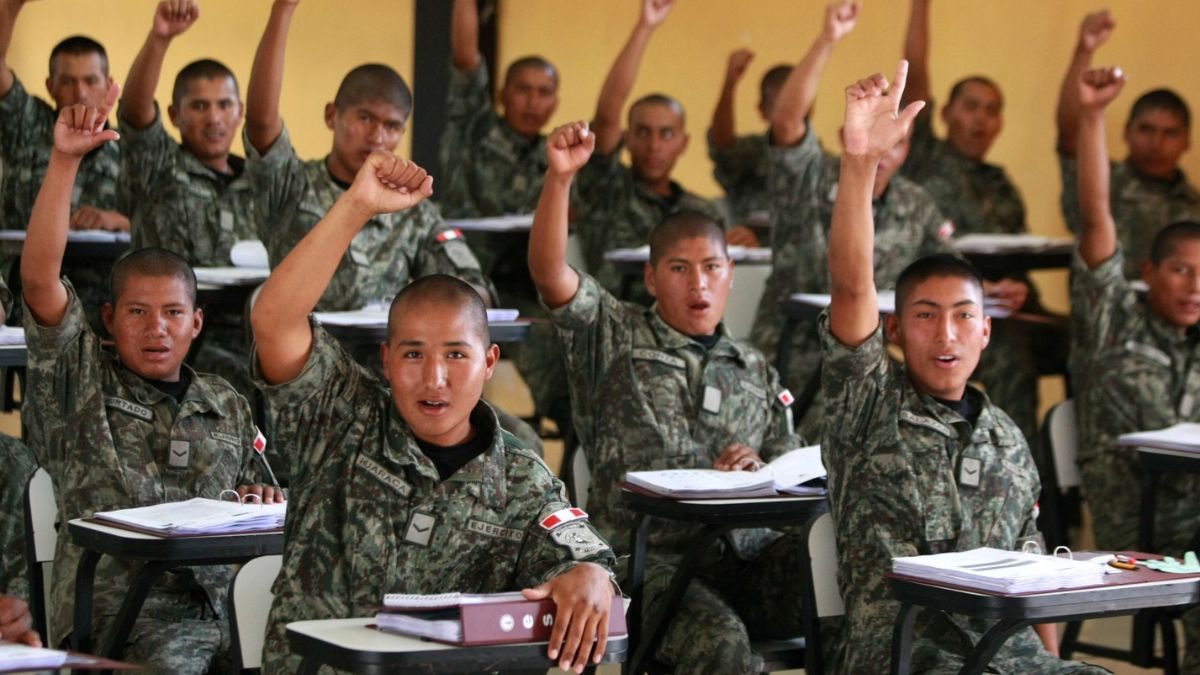 Grupo de militares en clase con la mano levantada