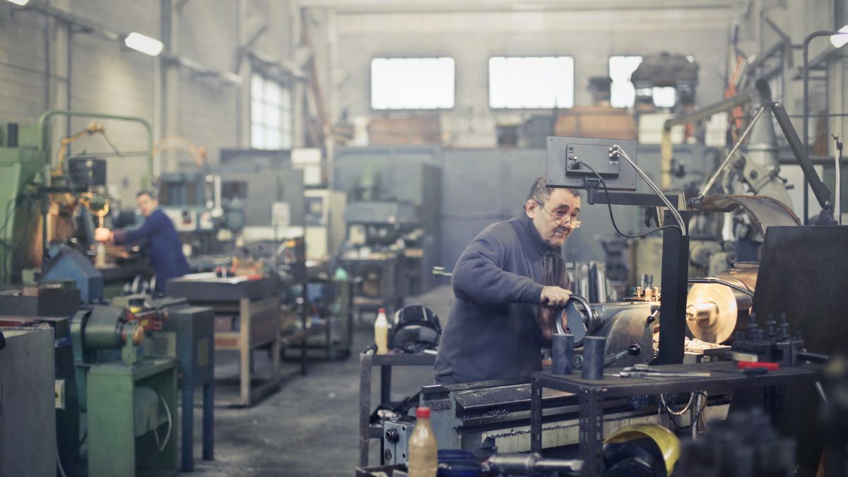 Un trabajador sénior durante su jornada de trabajo maneja una máquina
