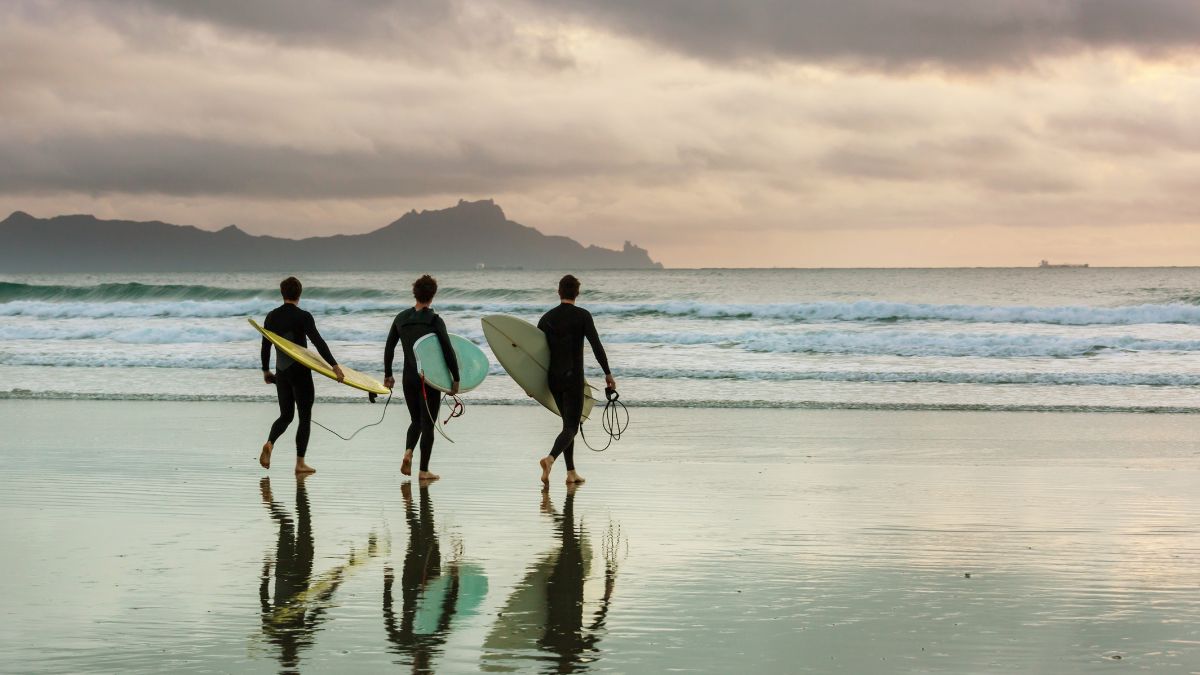 Varias personas haciendo surf en una playa.