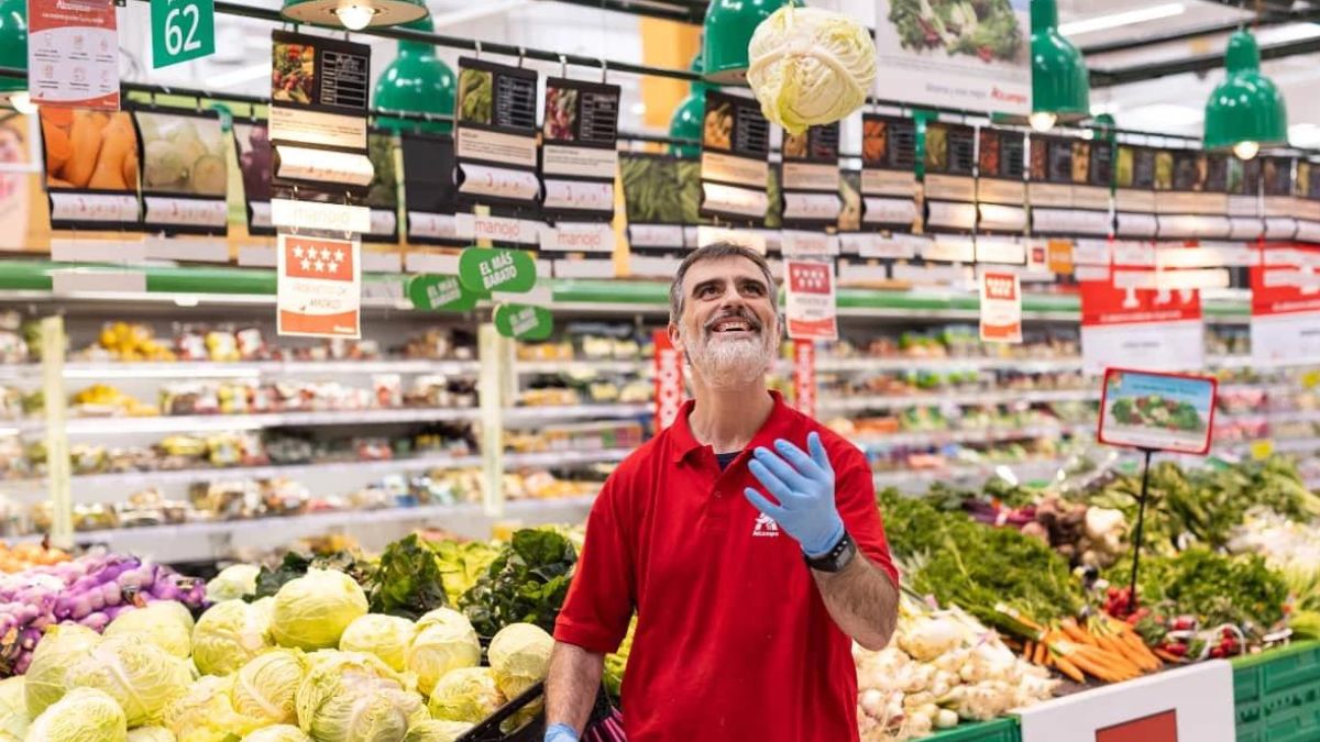 Un trabajador de Alcampo lanza una coliflor al aire en la sección de frutería.