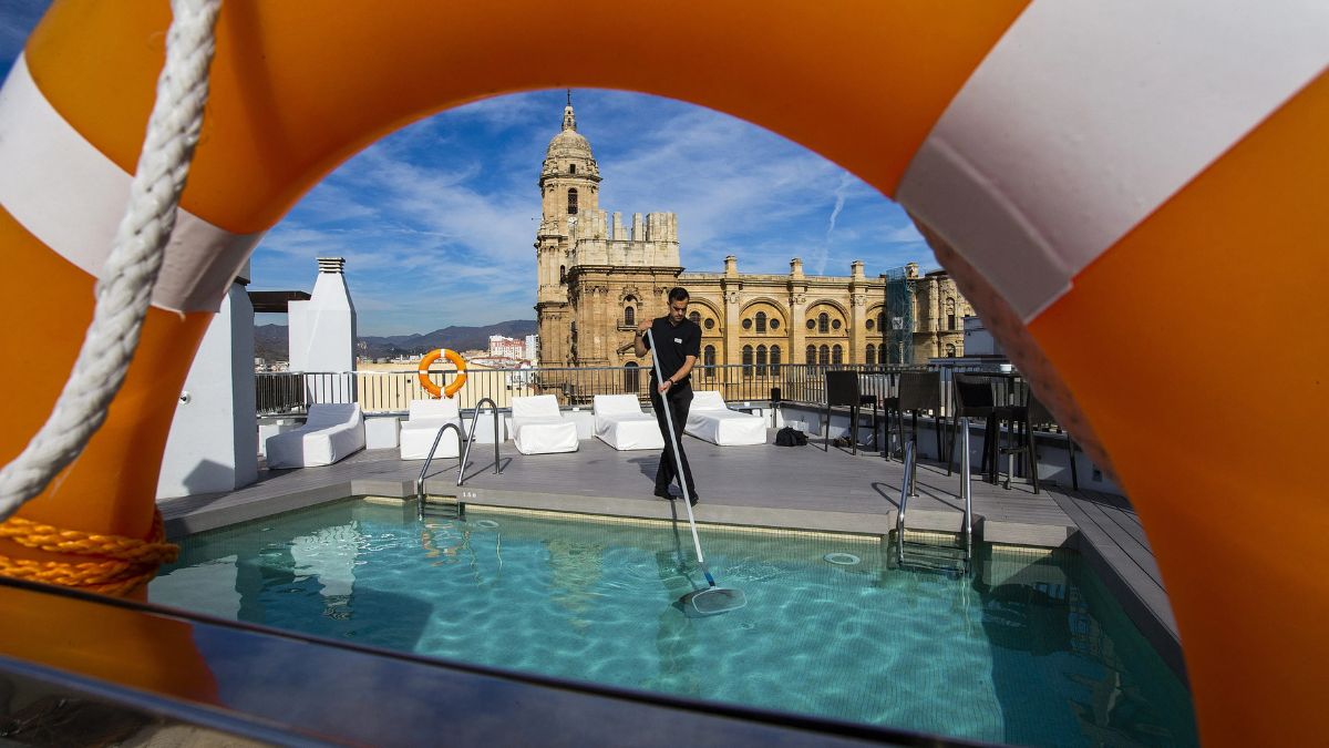 Un trabajador de hotel arregla la piscina.